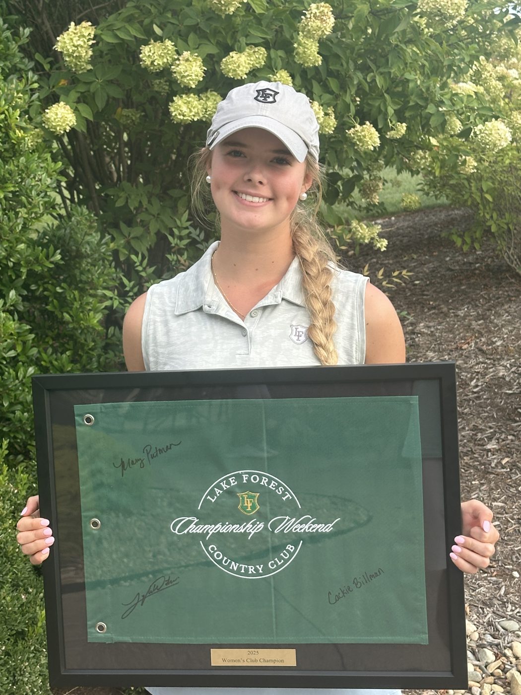Lyla holding the framed Lake Forest Country Club championship flag